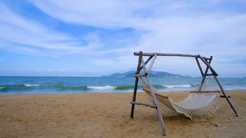 An empty hammock strung between two wooden pile on the sandy beach Stock Footage 101416067