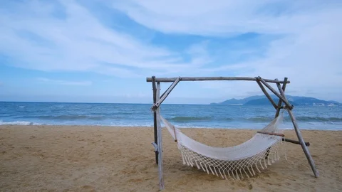 An empty hammock strung between two wooden pile on the sandy beach Stock Footage 101416118