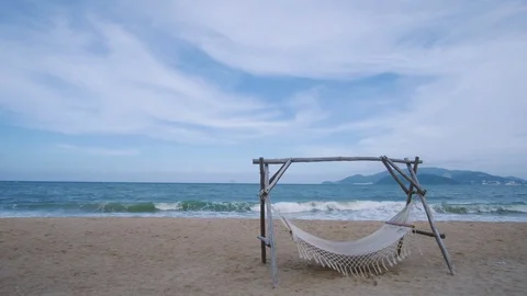 An empty hammock strung between two wooden pile on the sandy beach Stock Footage 101416265