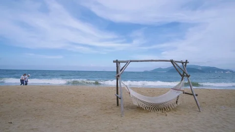 An empty hammock strung between two wooden pile on the sandy beach Stock Footage 101416356