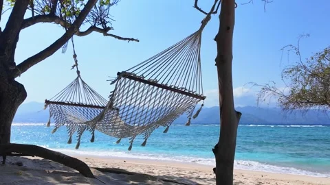 Empty hammock swaying gently against serene ocean backdrop on tropical beac.. Stock Footage 330986507