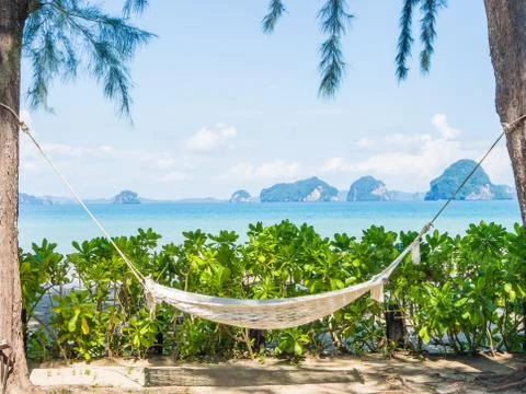 Empty hammock on the tropical beach with trees and beautiful sea view backgro Stock Photos