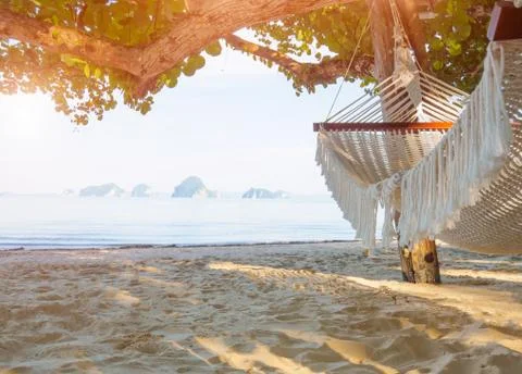 Empty hammock on the tropical beach with trees and beautiful sea view backgro Stock Photos