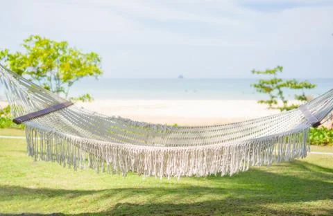 Empty hammock under palm trees at tropical beach resort with ocean on back Stock Photos