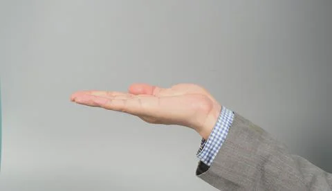 Empty hand to hold something straight in grey suit on grey background. Busine Stock Photos