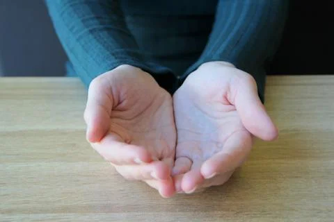 Empty hands folded together with palms up on light background Stock Photos