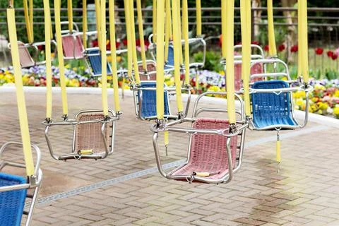 Empty hanging seats of a children's carousel in an amusement park. Selective Stock Photos