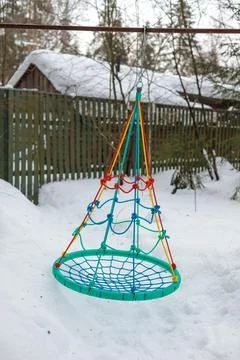Empty hanging swing nest on the background of a snow-covered rural landscape. Stock Photos