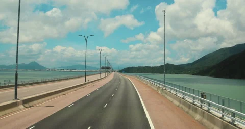 Empty highway bridge over sea with coastal mountains and blue sky Stock Footage 345501897