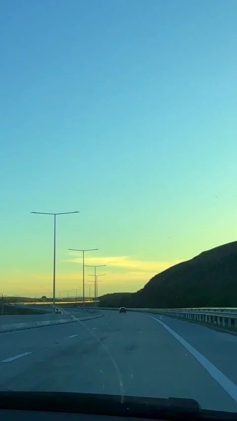 Empty Highway Curving Through Hills Under Blue and Golden Sunset Sky Stock Footage 310210739