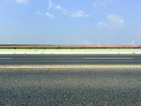Empty Highway with Distant Suspension Bridge under Clear Blue Sky 스톡 사진