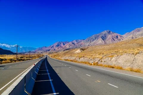 Empty highway road with separating concrete barrier in mountains at sunny autumn Stock Photos