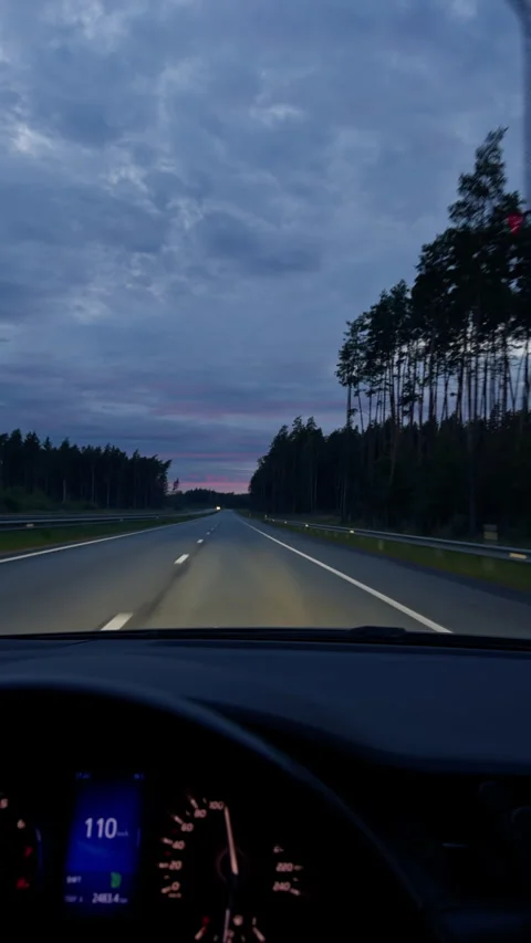 Empty highway through forest at dusk viewed from car interior with glowing Stock Footage 345452405