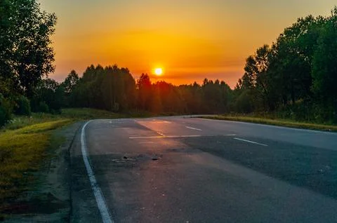An empty highway through the forest in the early morning at dawn. Stock Photos