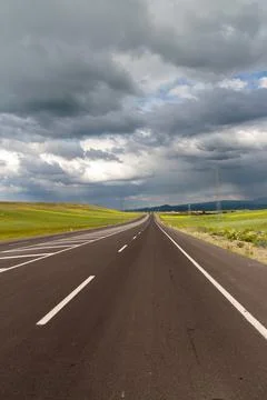 Empty Highway Through Green Fields Under Stormy Sky Stock Photos