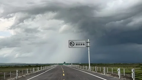 Empty Highway on Tibetan Plateau Under Dark Storm Clouds with Chinese Sign 動画素材 336008296