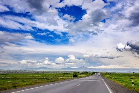 Empty highway under dramatic sky with clouds and mountains in distance Stock Photos