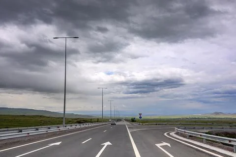 Empty highway under dramatic, stormy clouds Stock Photos