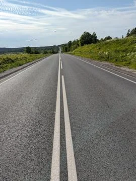 An empty highway under the sky, lined with white parallel stripes Stock Photos