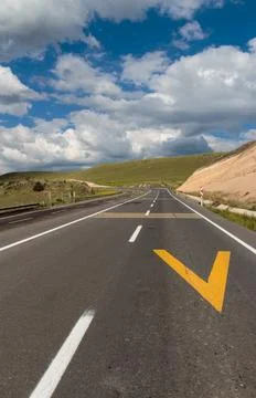 Empty Highway with Yellow Chevron Marking in Scenic Landscape Stock Photos