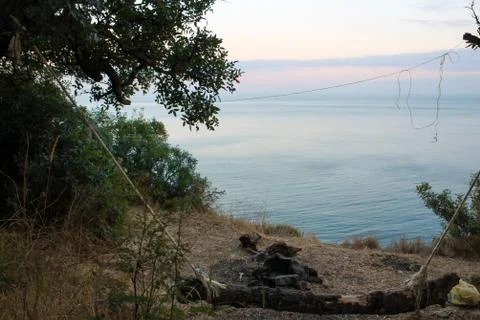 Empty home-made swing, an extinct fire. Seashore in the evening Foto stock