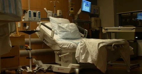 An empty hospital bed is revealed during night time at a hospital with sheets Stock Footage