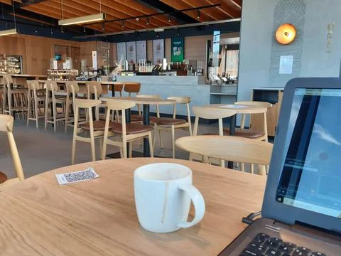 Empty hot drink mug inside Starbucks cafe coffee shop with laptop on table Stock Photos