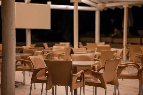 Empty Hotel Beach Cafe With Plastic Chairs And Tables At Night Moraitika, Corfu Stock Photos