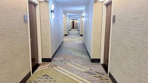 Empty hotel hallway with patterned carpet and doors Stock Photos
