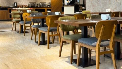Empty hotel restaurant dining area with wooden tables and upholstered chairs. Stock Photos