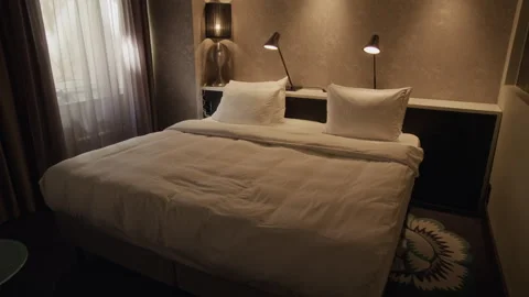 Empty Hotel Room Featuring Large Bed with Linens and Glowing Lamps Stock Footage 342124845