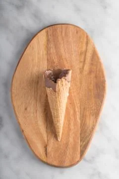 An empty ice cream cone put on a piece of wood. Stock Photos