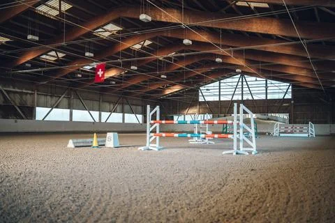 Empty indoor arena setup for show jumping with colorful obstacles and a swiss Foto stock