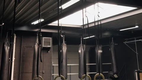 Empty indoor gym with hanging punching bags and gymnastic rings. Vidéo 332801616