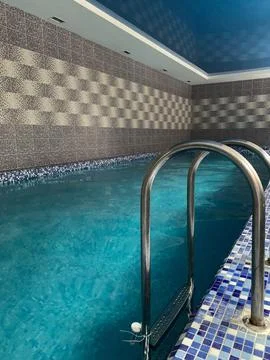 Empty Indoor Swimming Pool with Blue Tiled Walls and Metal Ladder Stock Photos