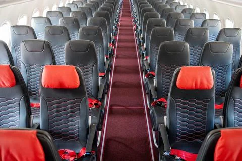 Empty interior of cabin of airplane with rows of black and red seats, High angle Stock Photos