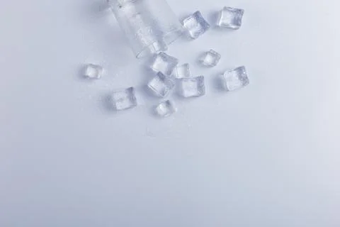 Empty inverted fallen glass with ice, on a white background. Stock Photos