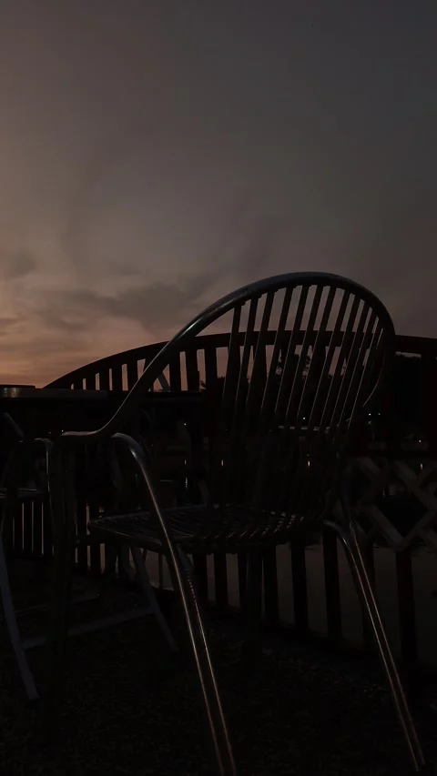 Empty iron chair on the edge of the river fence with a sunset sky background Stock Footage 313286076