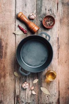 Empty iron pot and kitchen utensils on wooden background. Top view. Copy space Stock Photos