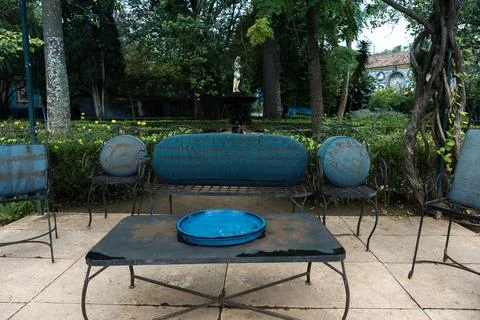 Empty iron table, chairs and bench with blue cushions in the park. Stock Photos