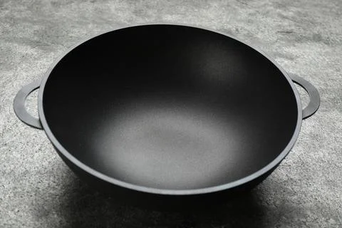 Empty iron wok on grey table. Chinese cookware Stock Photos