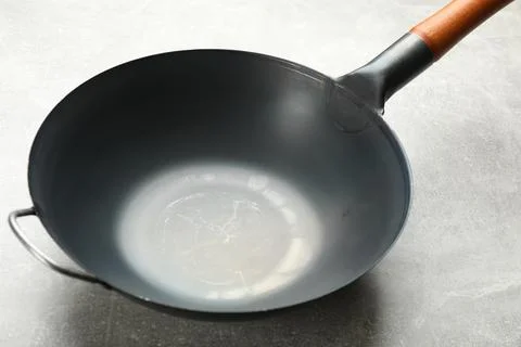 Empty iron wok on grey table. Chinese cookware Stock Photos