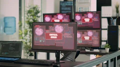 Empty it office desk with multiple computers showing security breach warning 写真素材