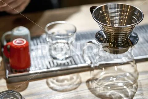 Empty kettle, glass, cups and coffee wave dripper on table Stock Photos