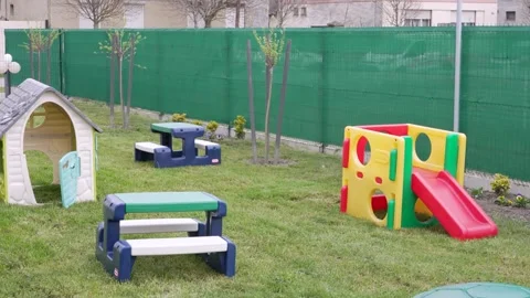 Empty kindergarten backyard with colorful plastic playground equipment on green Stock Footage 339754659