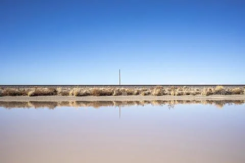 Empty landscape blue sky train tracks reflection in puddle Stock Photos