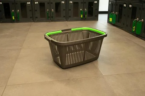 Empty laundry basket in a locker room with gray tiles and storage lockers a.. Stock Photos