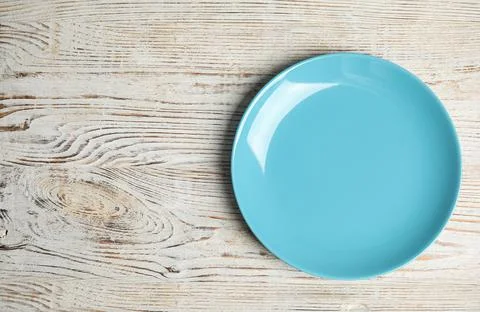 Empty light blue plate on white wooden table, top view. Space for text Stock Photos