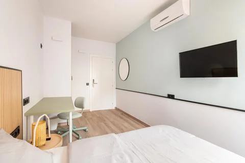 Empty light room with bed, desk, desk and air-conditioner and TV on light green Stock Photos