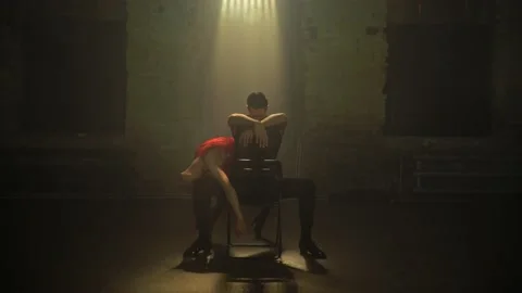 Empty loft room,young man sits on chair in center,woman starts dancing around Stock Footage 230201843